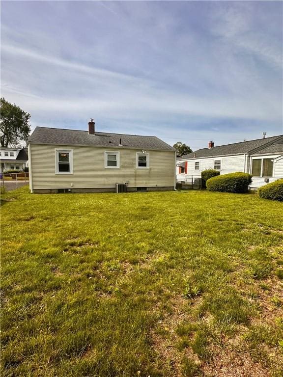 100 Benedict St, Pawtucket, RI 02861 - back of property featuring a lawn, central AC unit, and a chimney