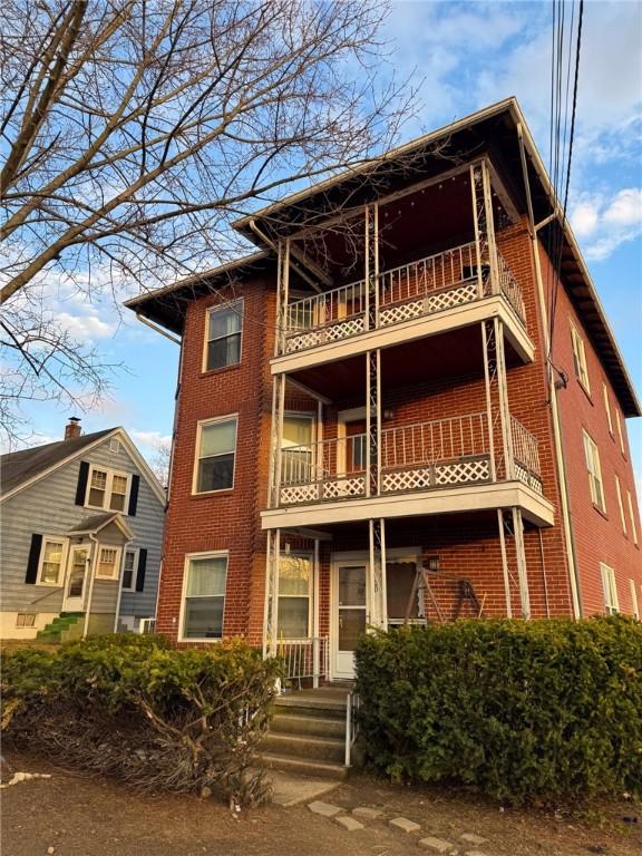 20 Vivian Ave, Cumberland, RI 02864 - view of front of house with a balcony and brick siding