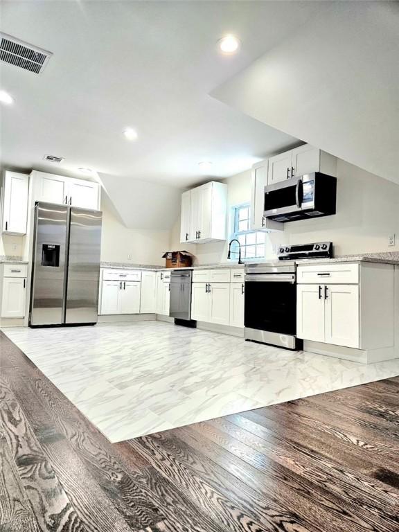 90 Grove St, Providence, RI 02903 - kitchen featuring appliances with stainless steel finishes, white cabinets, recessed lighting, and lofted ceiling