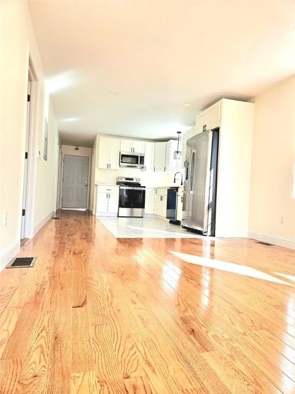 90 Grove St, Providence, RI 02903 - unfurnished living room with light wood-type flooring and baseboards