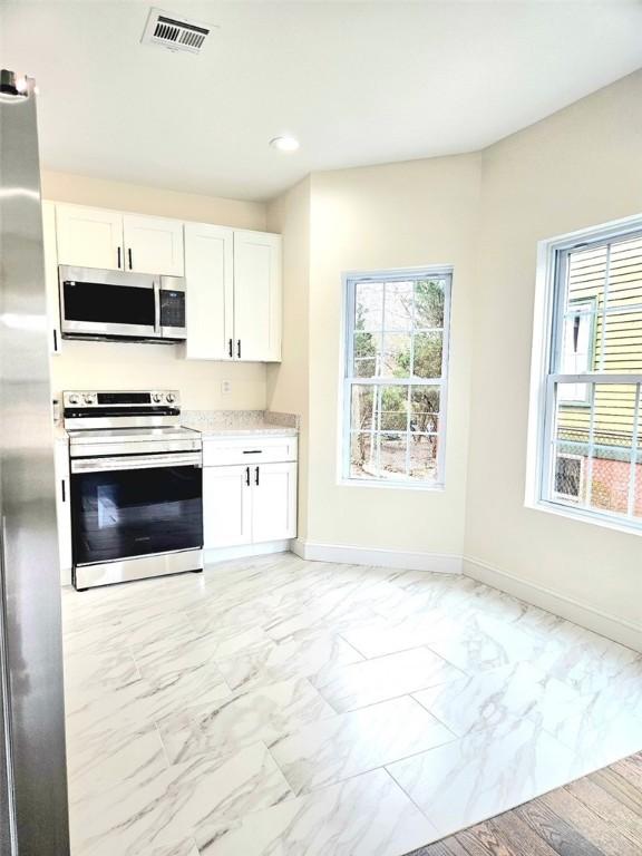 90 Grove St, Providence, RI 02903 - kitchen with stainless steel appliances, baseboards, white cabinetry, light countertops, and recessed lighting