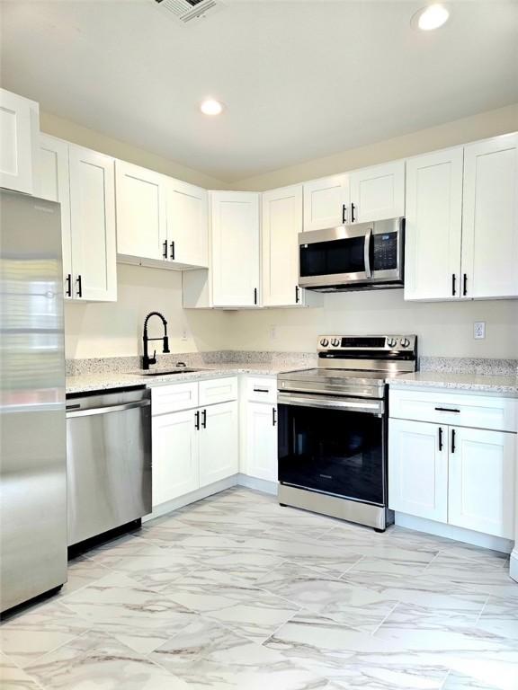 90 Grove St, Providence, RI 02903 - kitchen featuring appliances with stainless steel finishes, light marble finish flooring, recessed lighting, a sink, and white cabinetry