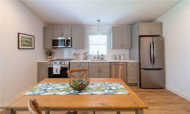 32 Exchange St Unit 104, East Greenwich, RI 02818 - kitchen with stainless steel appliances, a sink, gray cabinets, light countertops, and tasteful backsplash