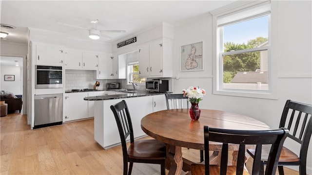 21 Meadowrue Trl, Narragansett, RI 02874 - kitchen with stainless steel appliances, a peninsula, dark countertops, light wood-type flooring, and white cabinets