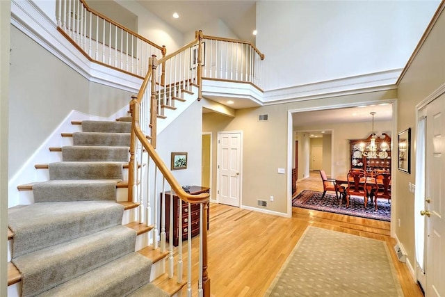 60 Pheasant Dr, East Greenwich, RI 02818 - stairs featuring wood finished floors, a chandelier, baseboards, a towering ceiling, and recessed lighting