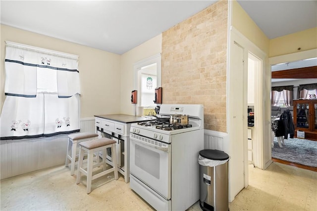 1362 Newport Ave, Pawtucket, RI 02861 - kitchen featuring white gas range oven, plenty of natural light, wainscoting, and light flooring
