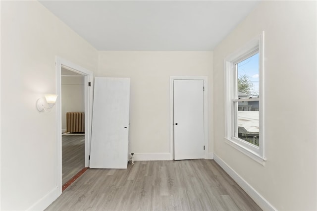 1875 Smith St, North Providence, RI 02911 - unfurnished bedroom with light wood-type flooring, radiator, and baseboards