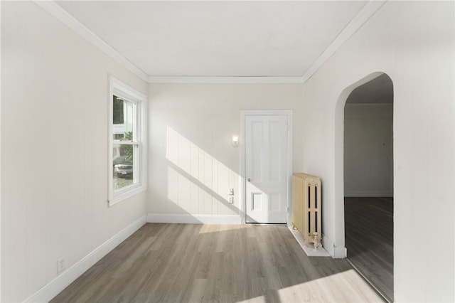 1875 Smith St, North Providence, RI 02911 - spare room with radiator, arched walkways, wood finished floors, ornamental molding, and baseboards