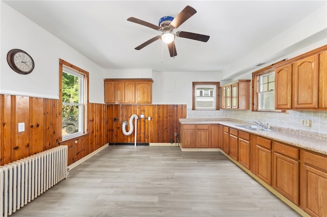 1875 Smith St, North Providence, RI 02911 - kitchen featuring radiator, wainscoting, light wood finished floors, light countertops, and a sink