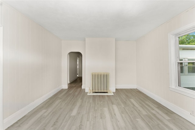 1875 Smith St, North Providence, RI 02911 - unfurnished room featuring radiator heating unit, arched walkways, wood finished floors, and baseboards