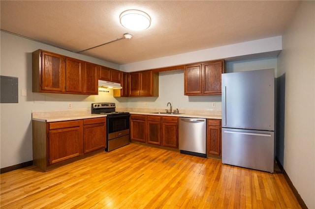 444 Woodward Rd Unit 23, North Providence, RI 02904 - kitchen with stainless steel appliances, under cabinet range hood, a sink, light countertops, and light wood finished floors