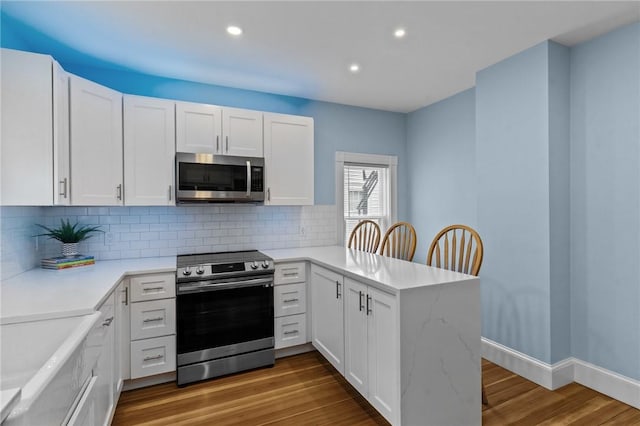 36 Ruth Ave, East Providence, RI 02916 - kitchen featuring appliances with stainless steel finishes, a peninsula, white cabinetry, tasteful backsplash, and recessed lighting