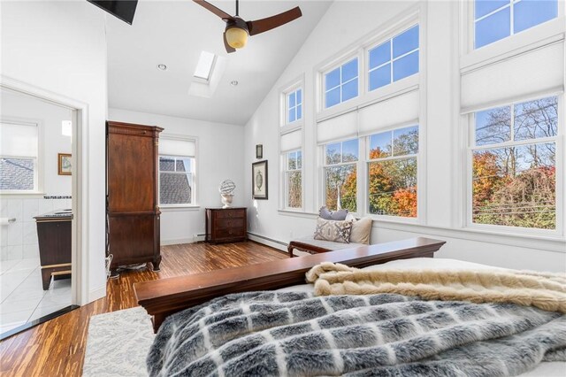 85 Frigate St, Jamestown, RI 02832 - bedroom featuring high vaulted ceiling, a skylight, wood finished floors, a baseboard radiator, and connected bathroom