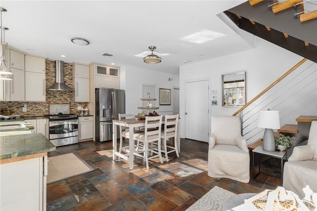 85 Frigate St, Jamestown, RI 02832 - kitchen featuring appliances with stainless steel finishes, wall chimney range hood, decorative backsplash, stone tile flooring, and dark countertops