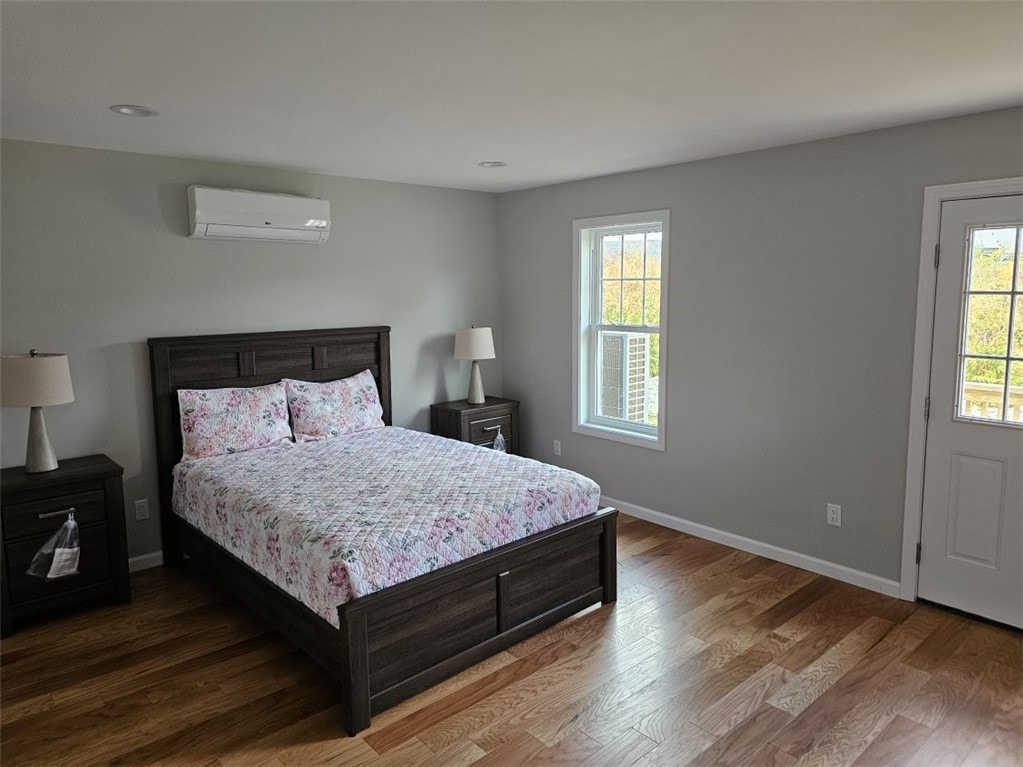 83 Ayda Rose Ave, West Warwick, RI 02893 - bedroom with a wall mounted air conditioner, baseboards, and wood finished floors
