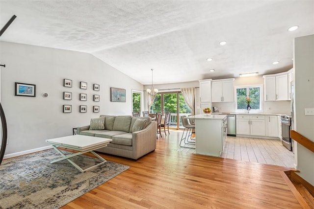 11 Noto Dr, North Providence, RI 02904 - living area with light wood-style flooring, a chandelier, vaulted ceiling, baseboards, and a textured ceiling