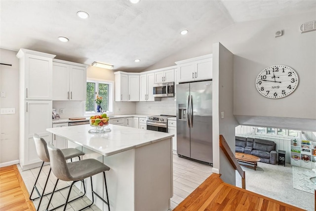11 Noto Dr, North Providence, RI 02904 - kitchen with stainless steel appliances, vaulted ceiling, light wood finished floors, white cabinetry, and tasteful backsplash