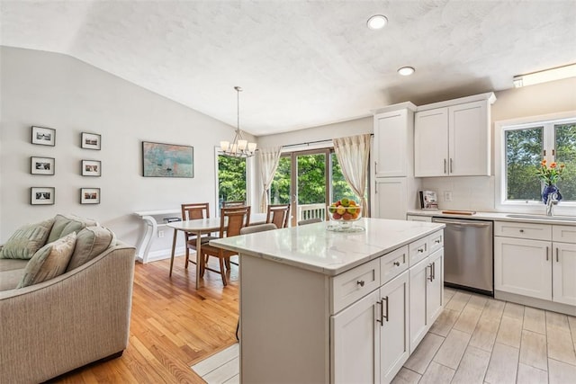 11 Noto Dr, North Providence, RI 02904 - kitchen with stainless steel dishwasher, vaulted ceiling, light wood-style floors, open floor plan, and white cabinetry