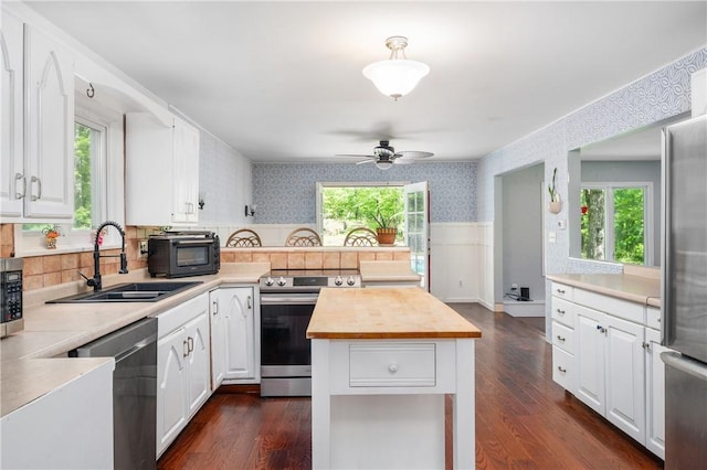 8 Westgate Rd, Cumberland, RI 02864 - kitchen with appliances with stainless steel finishes, wallpapered walls, a sink, a wainscoted wall, and white cabinetry