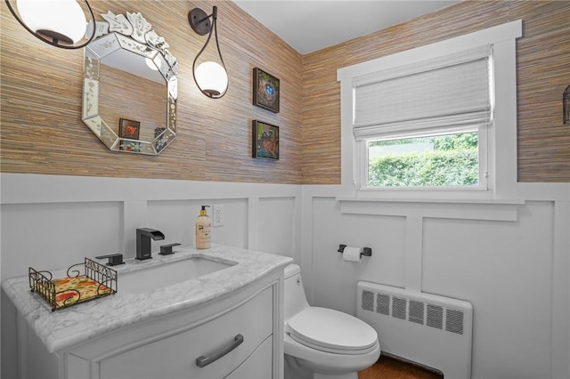 25 King Philip Rd, Pawtucket, RI 02861 - half bathroom with radiator heating unit, a decorative wall, vanity, and toilet