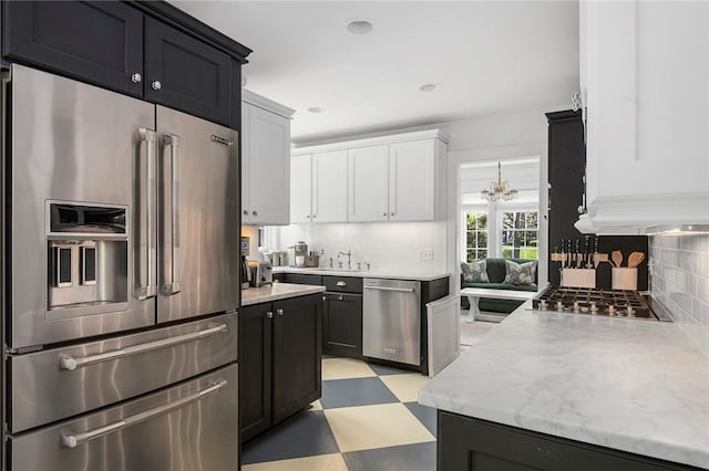34 Dryden Ave, Pawtucket, RI 02860 - kitchen with appliances with stainless steel finishes, light flooring, backsplash, white cabinetry, and dark cabinets