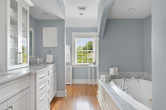 34 Dryden Ave, Pawtucket, RI 02860 - bathroom featuring vanity, a tub with jets, baseboards, and wood finished floors