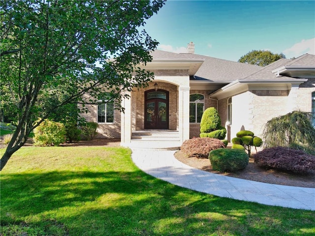 51 W Ridge Dr, Tiverton, RI 02878 - view of front of home with a front yard, brick siding, a chimney, french doors, and roof with shingles