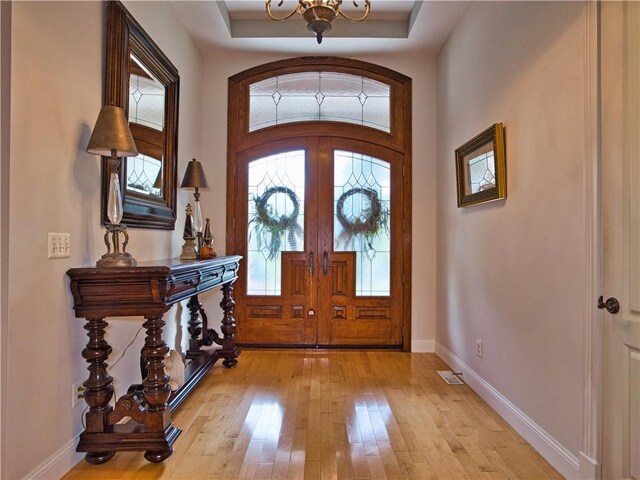 51 W Ridge Dr, Tiverton, RI 02878 - foyer featuring light wood-style floors, baseboards, a chandelier, arched walkways, and a raised ceiling