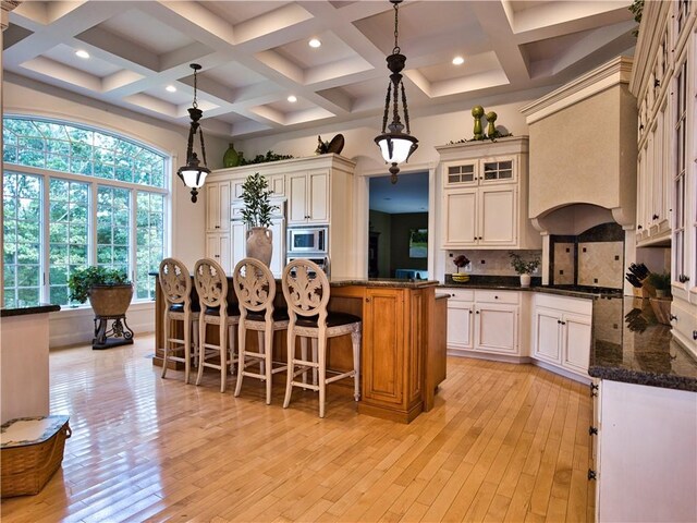 51 W Ridge Dr, Tiverton, RI 02878 - kitchen featuring appliances with stainless steel finishes, light wood finished floors, backsplash, a breakfast bar area, and coffered ceiling