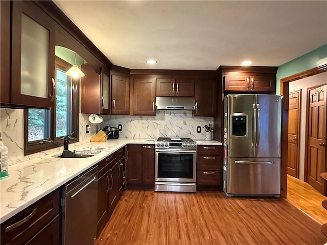 3945 Post Rd, Warwick, RI 02886 - kitchen with stainless steel appliances, a sink, under cabinet range hood, wood finished floors, and decorative backsplash
