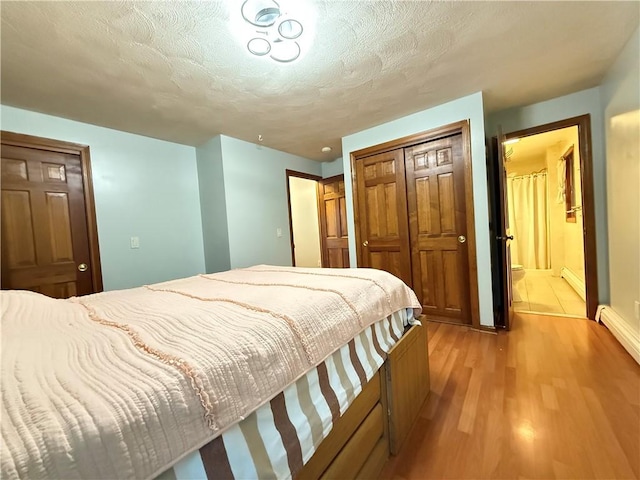 3945 Post Rd, Warwick, RI 02886 - bedroom featuring a closet, light wood-style floors, a textured ceiling, baseboards, and a baseboard radiator