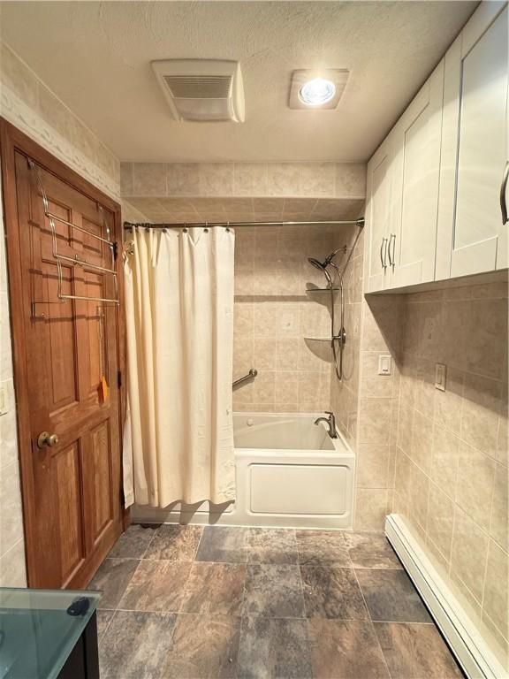 3945 Post Rd, Warwick, RI 02886 - full bathroom with a baseboard radiator, shower / tub combo, a textured ceiling, and tile walls