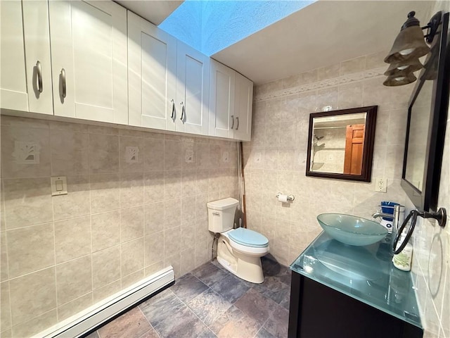 3945 Post Rd, Warwick, RI 02886 - bathroom with baseboard heating, vanity, toilet, tile walls, and stone finish floors