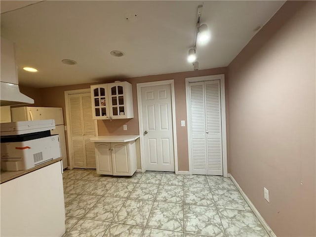 3945 Post Rd, Warwick, RI 02886 - kitchen featuring glass insert cabinets, light countertops, light marble finish flooring, baseboards, and recessed lighting