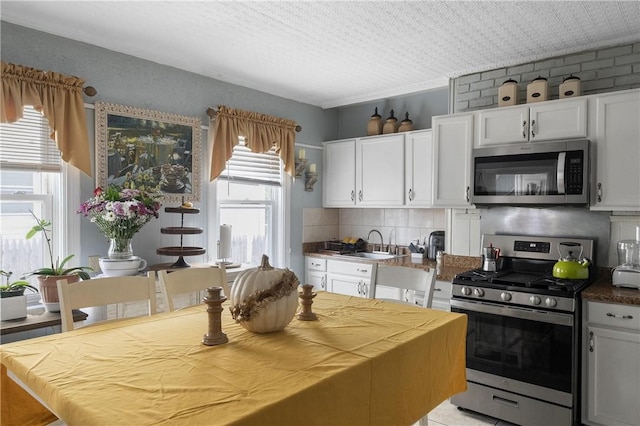 15 Ruggles St, Providence, RI 02908 - kitchen with appliances with stainless steel finishes, white cabinetry, tasteful backsplash, and a sink
