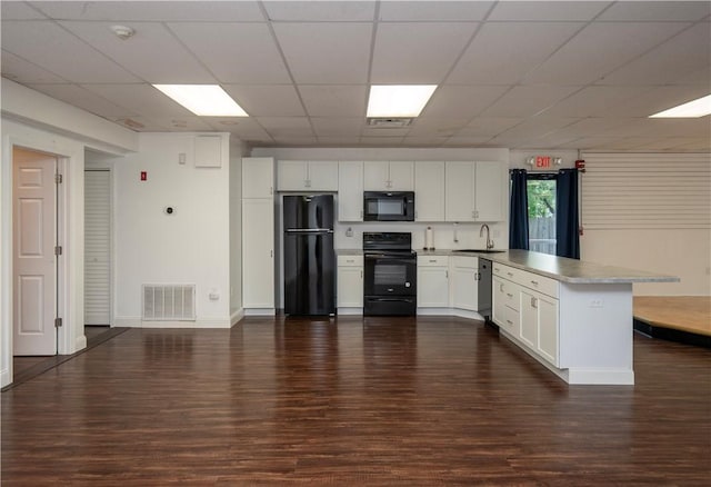 413 High St, Bristol, RI 02809 - kitchen with black appliances, a peninsula, dark wood-style flooring, white cabinetry, and a paneled ceiling