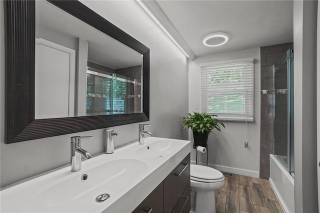 15 Lawnacre Dr, North Providence, RI 02911 - bathroom with double vanity, wood finished floors, toilet, baseboards, and bath / shower combo with glass door