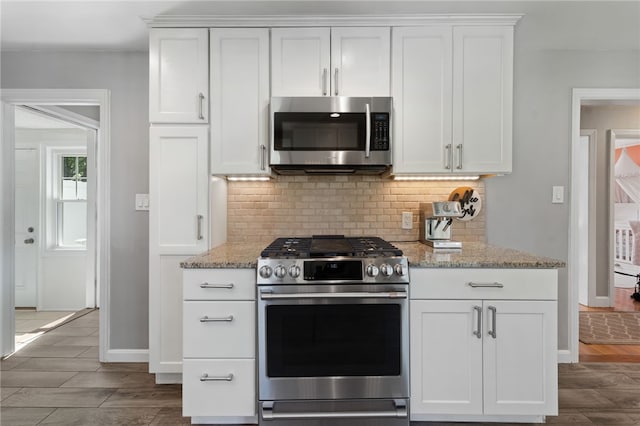 23 Revere St, Pawtucket, RI 02861 - kitchen with stainless steel appliances, decorative backsplash, white cabinets, light stone countertops, and wood tiled floors