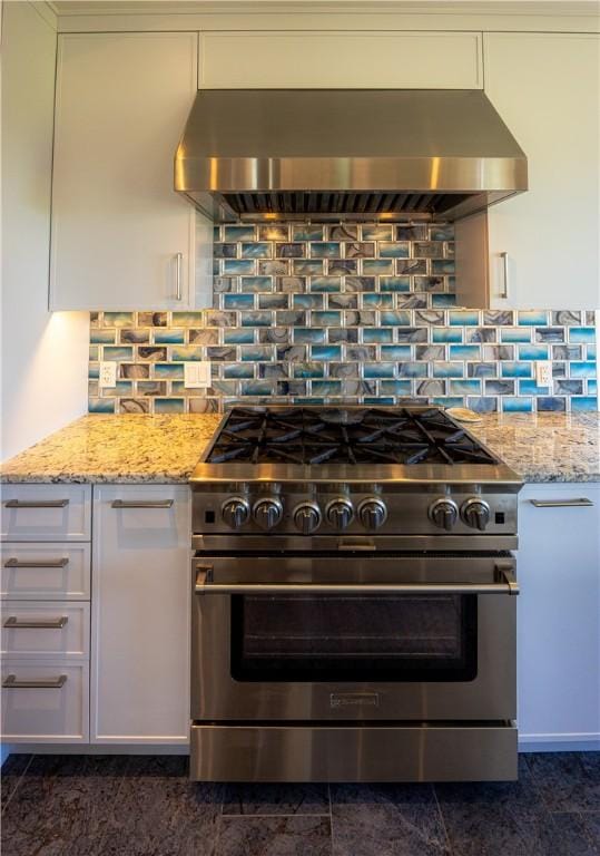 1448 Mohegan Trl, Block Island, RI 02807 - kitchen with high end stainless steel range, wall chimney exhaust hood, white cabinetry, light stone counters, and backsplash