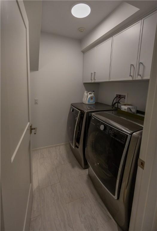 1448 Mohegan Trl, Block Island, RI 02807 - laundry area featuring washing machine and dryer, cabinet space, light marble finish floors, and baseboards
