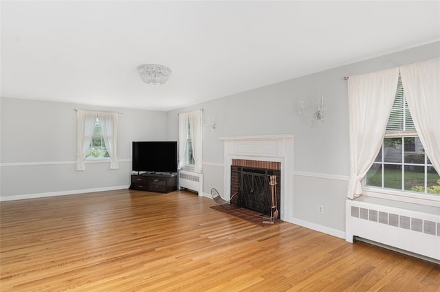 15 Metcalf Dr, Cumberland, RI 02864 - unfurnished living room featuring radiator, light wood-style floors, and a brick fireplace