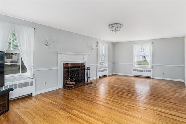 15 Metcalf Dr, Cumberland, RI 02864 - unfurnished living room with radiator heating unit, light wood-style flooring, and a brick fireplace