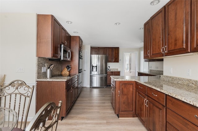 15 Metcalf Dr, Cumberland, RI 02864 - kitchen featuring appliances with stainless steel finishes, light wood-style flooring, a peninsula, light stone counters, and tasteful backsplash