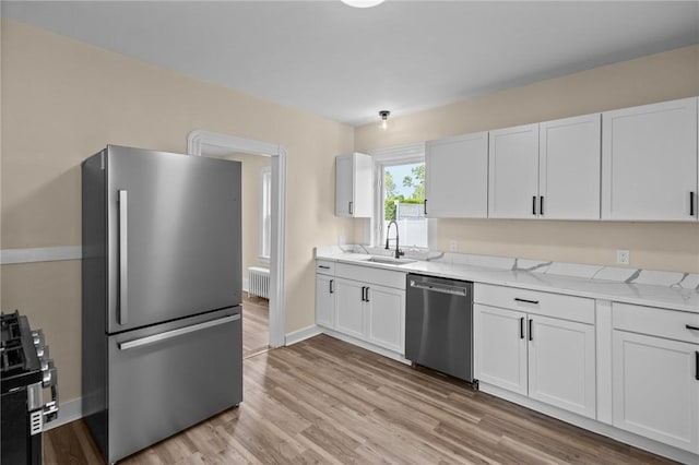 62 Fenner Ave, East Providence, RI 02915 - kitchen with appliances with stainless steel finishes, a sink, white cabinets, and light wood-style flooring