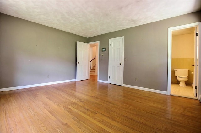 40 Boombridge Rd, Westerly, RI 02891 - unfurnished bedroom featuring light wood-style flooring, baseboards, ensuite bath, and a textured ceiling