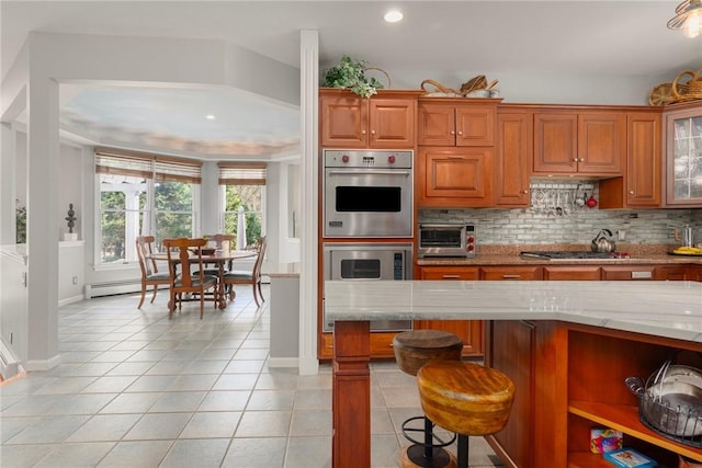 95 Pheasant Dr, East Greenwich, RI 02818 - kitchen with light tile patterned floors, light stone counters, brown cabinetry, appliances with stainless steel finishes, and recessed lighting