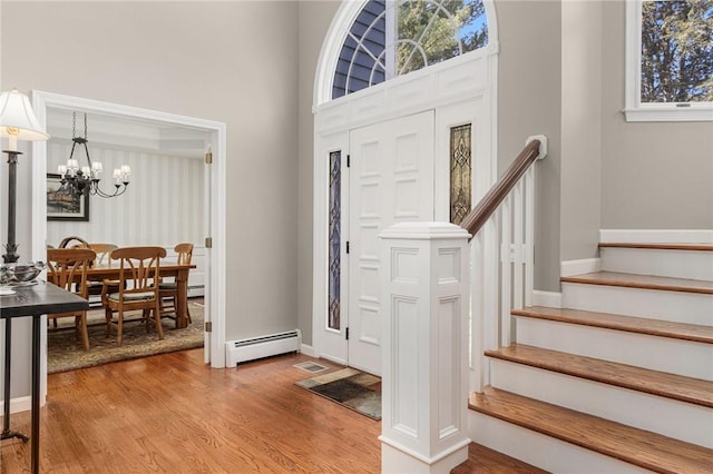 95 Pheasant Dr, East Greenwich, RI 02818 - foyer with a baseboard radiator, a chandelier, light wood-style flooring, stairs, and a high ceiling