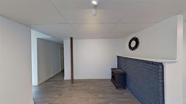 370 Ring Ave, Warwick, RI 02888 - unfurnished living room featuring a drop ceiling, wood finished floors, a wood stove, and baseboards