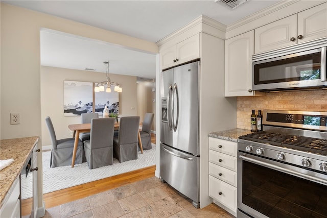 45 Landon Rd, Warwick, RI 02888 - kitchen featuring stainless steel appliances, decorative backsplash, light stone countertops, a chandelier, and decorative light fixtures
