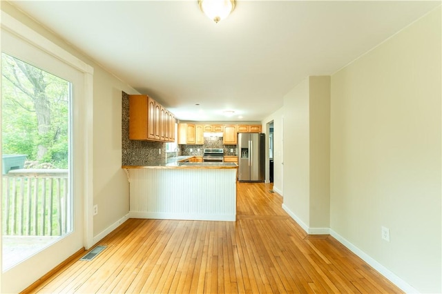 235 Spring St, Hopkinton, RI 02832 - kitchen with appliances with stainless steel finishes, a peninsula, light wood-style floors, backsplash, and a sink